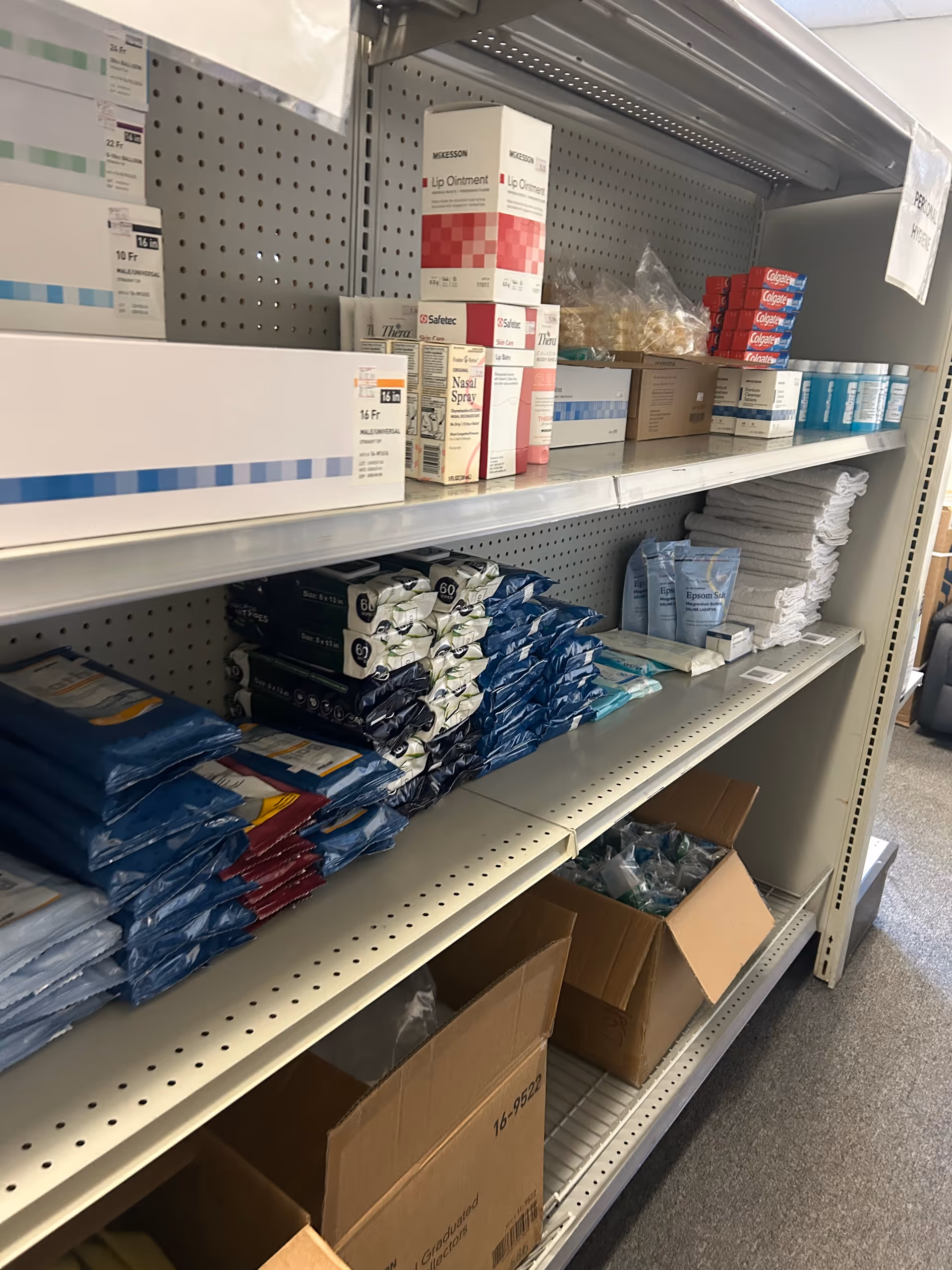 Shelf stocked with medical supplies on a facility storage aisle.