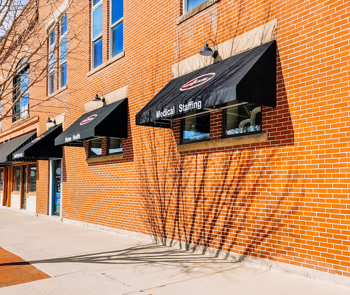 Brick building exterior with black awnings over windows reading Medical Staffing and Home Health.