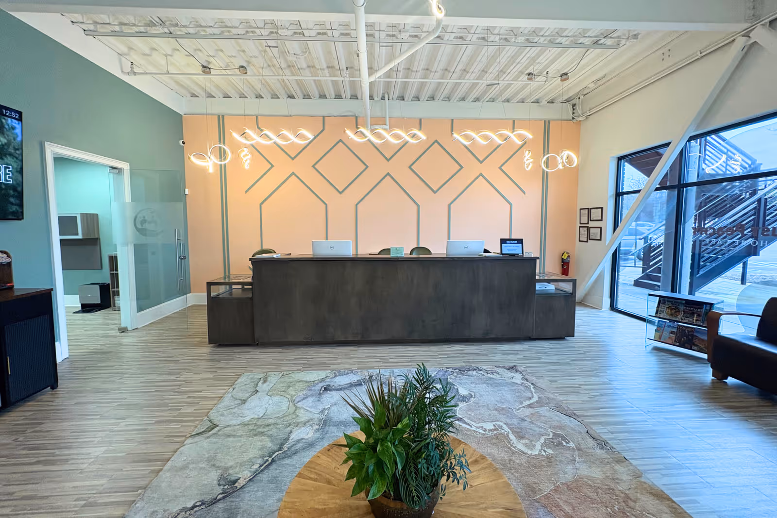 Reception desk in a modern lobby with a peach geometric wall behind and a plant.