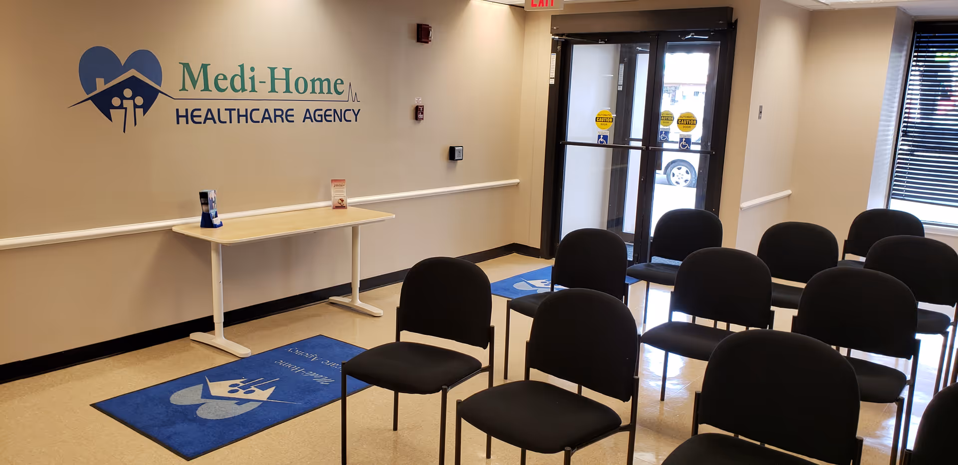 Waiting area inside Medi-Home Healthcare Agency with rows of chairs and a logo on the wall.