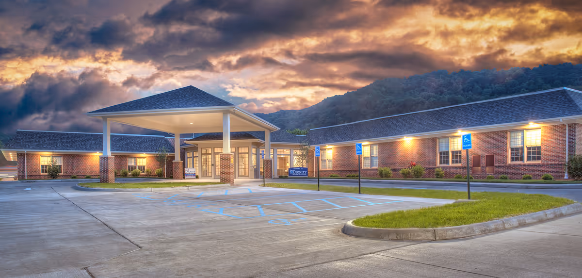 Exterior view of a brick senior living facility with a covered entrance and parking.