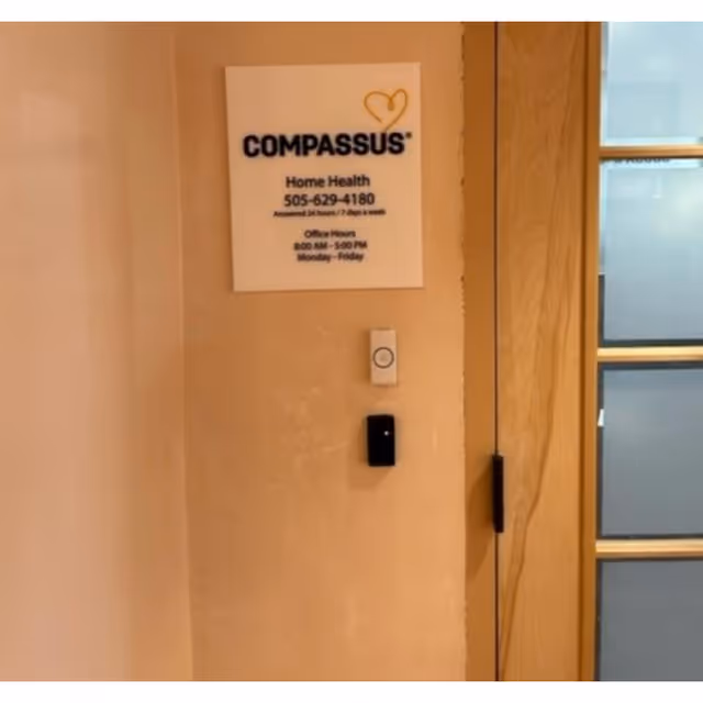 Interior wall with Compassus Home Health sign near a glass-paneled door.