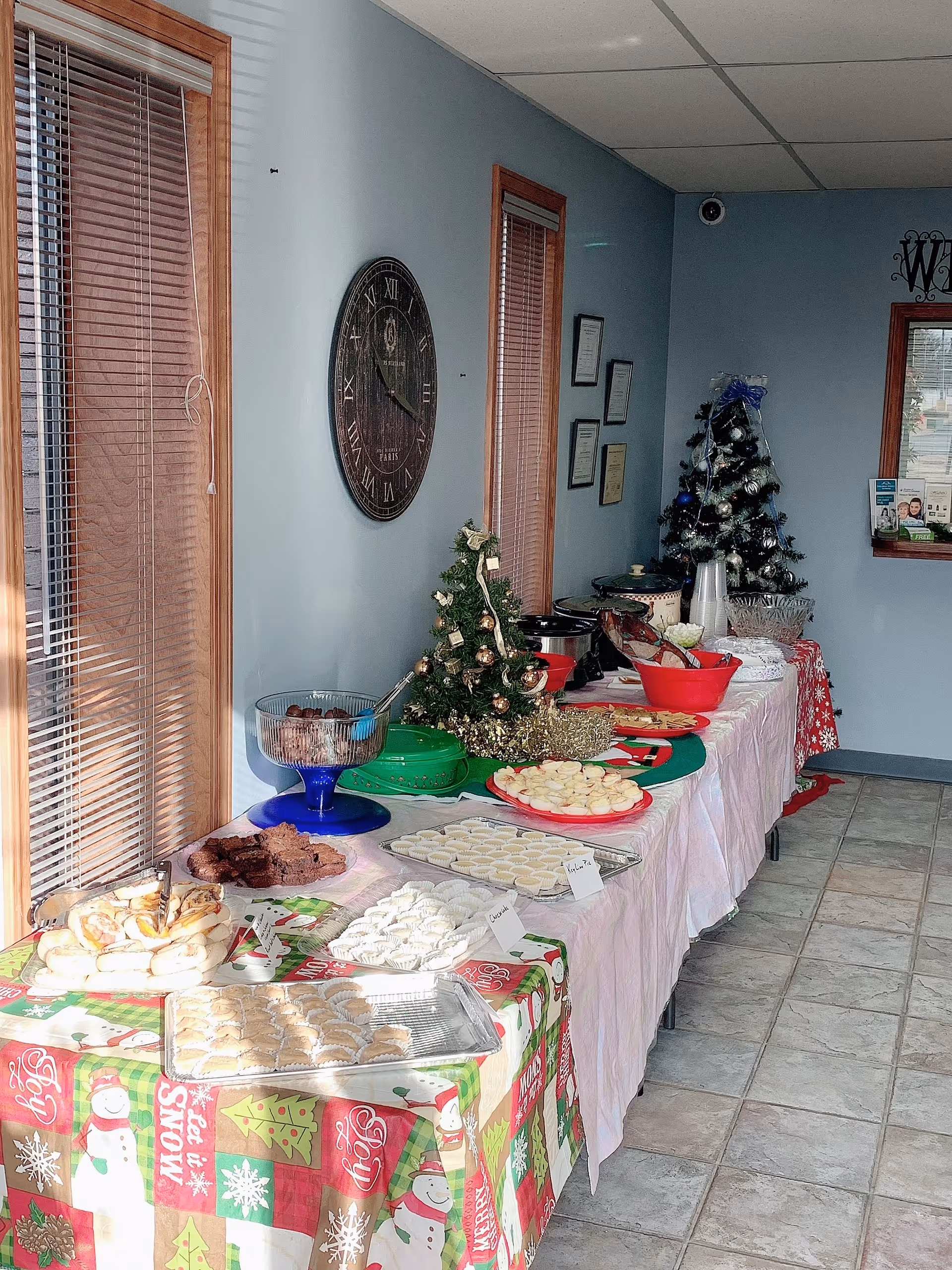 Interior hallway with a long table of holiday desserts and a small Christmas tree.