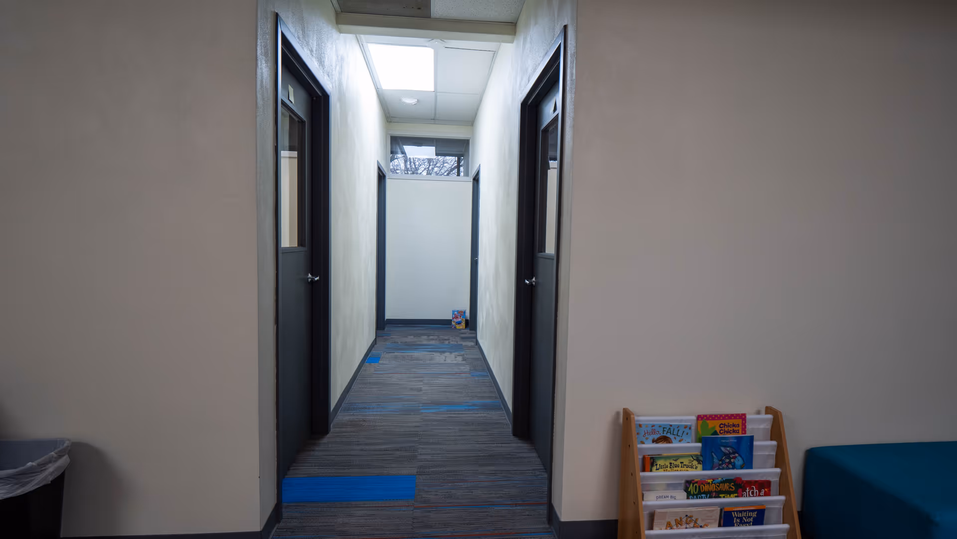 Narrow interior hallway with closed doors on both sides and a magazine rack.