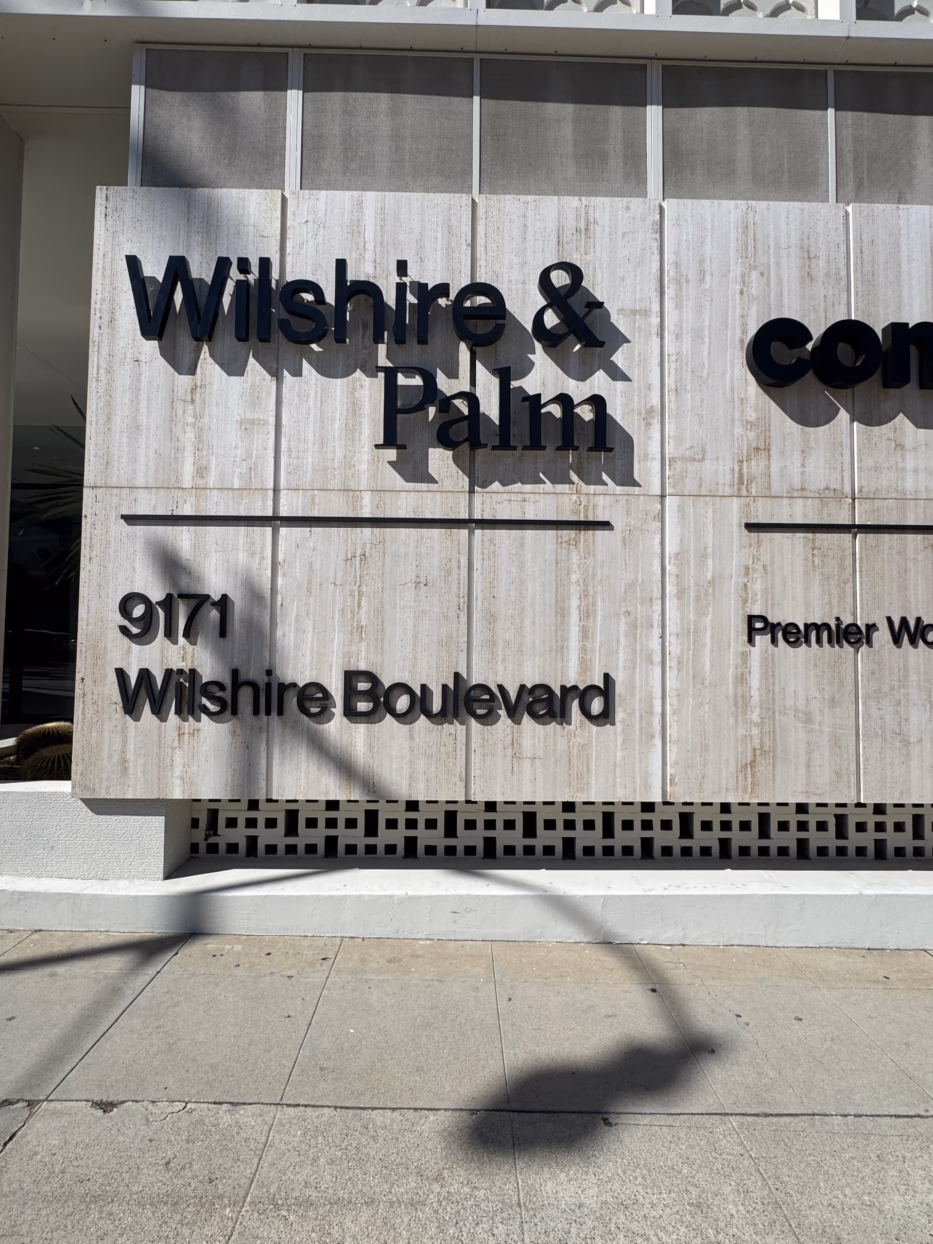 Exterior sign reads Wilshire & Palm and Wilshire Boulevard on a modern facade.