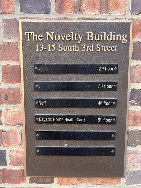 Bronze plaque on brick wall listing floors and tenants for The Novelty Building.