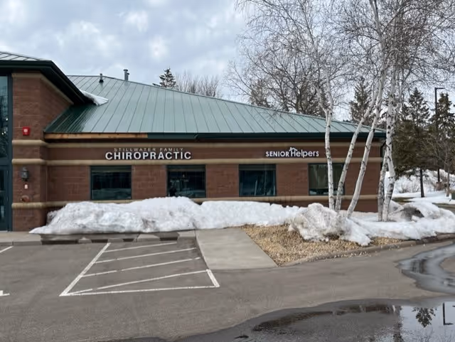 Exterior view of a brick building with Senior Helpers and chiropractic signs in snow.