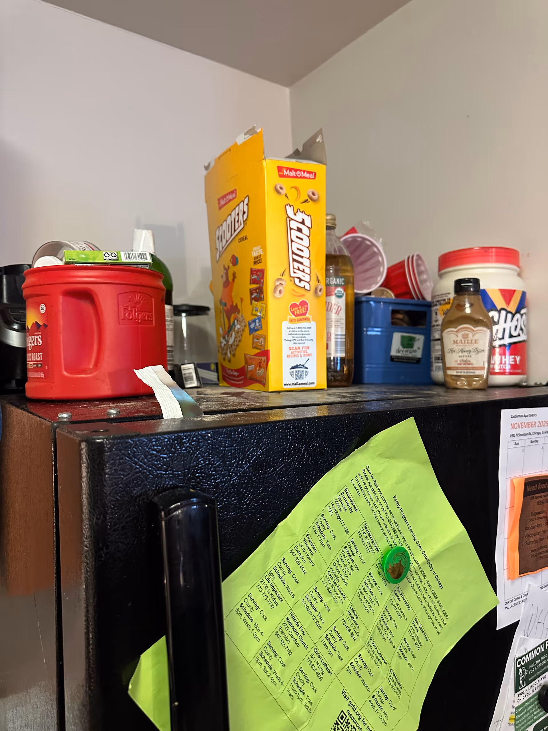 A kitchen counter in an interior facility showing a cereal box, red appliance, and assorted containers.
