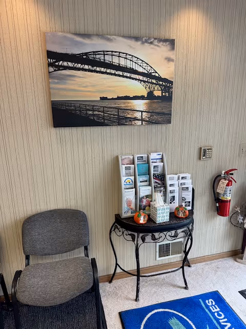 Lobby area with brochure stand, two gray chairs, wall art, and a fire extinguisher.