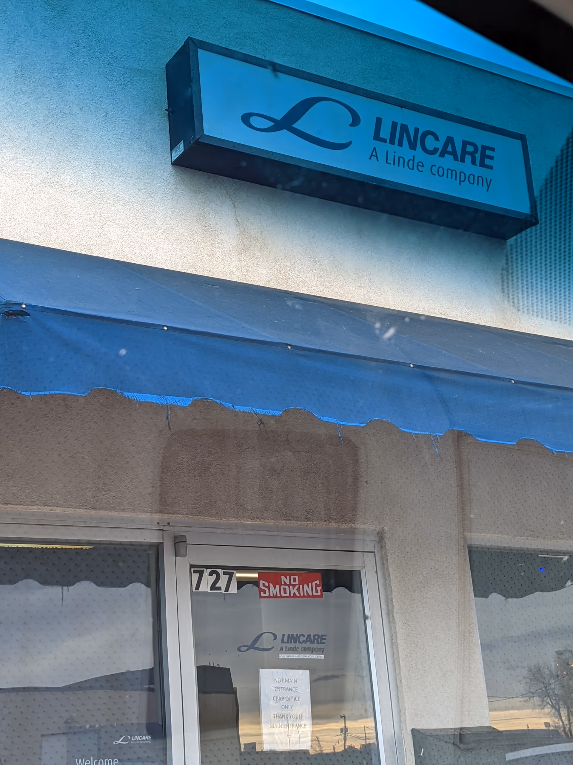 Exterior entrance of LINCARE facility with blue awning and sign.