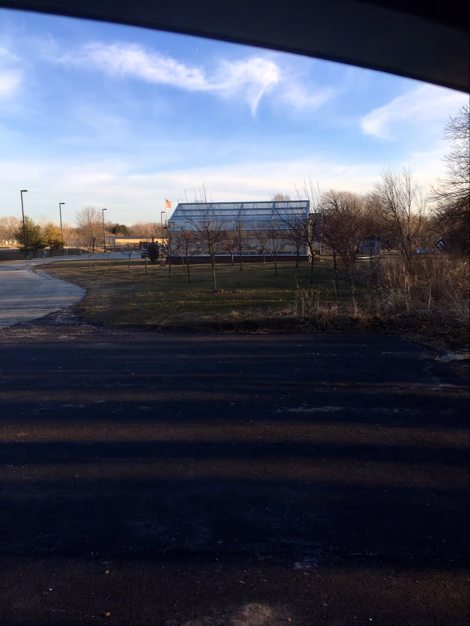 Exterior view of a Compassus facility with a glass-roofed building and bare trees.
