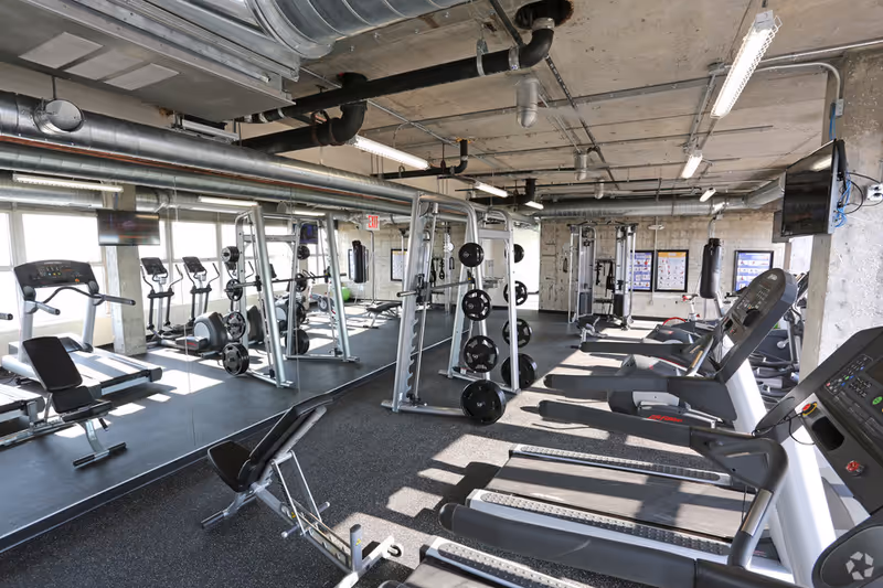 Industrial-style interior gym at Serenity Home Care with treadmills, weight machines, and mirrored walls.
