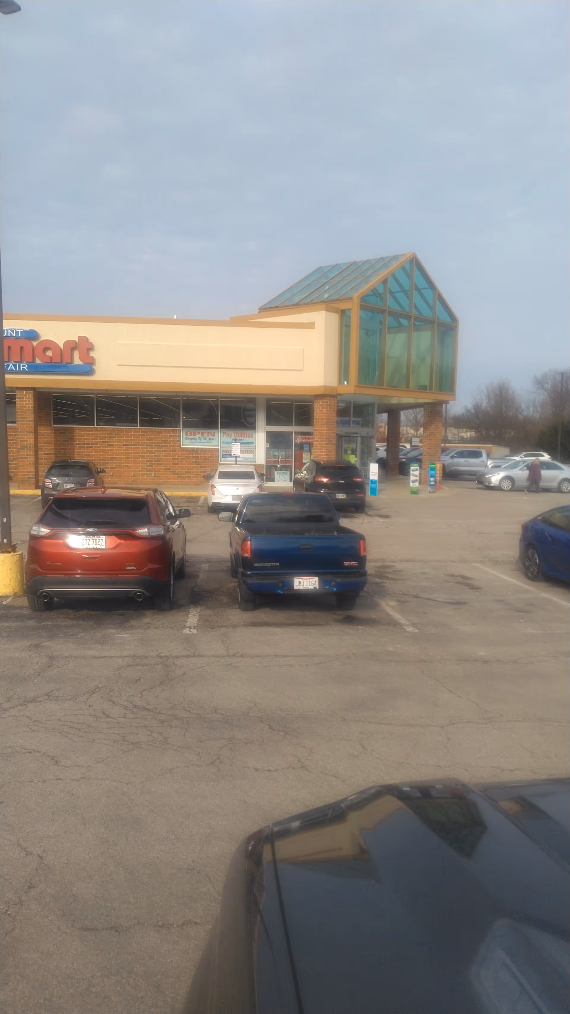 Discount Drug Mart storefront with glass entry, brick facade, and several parked cars.