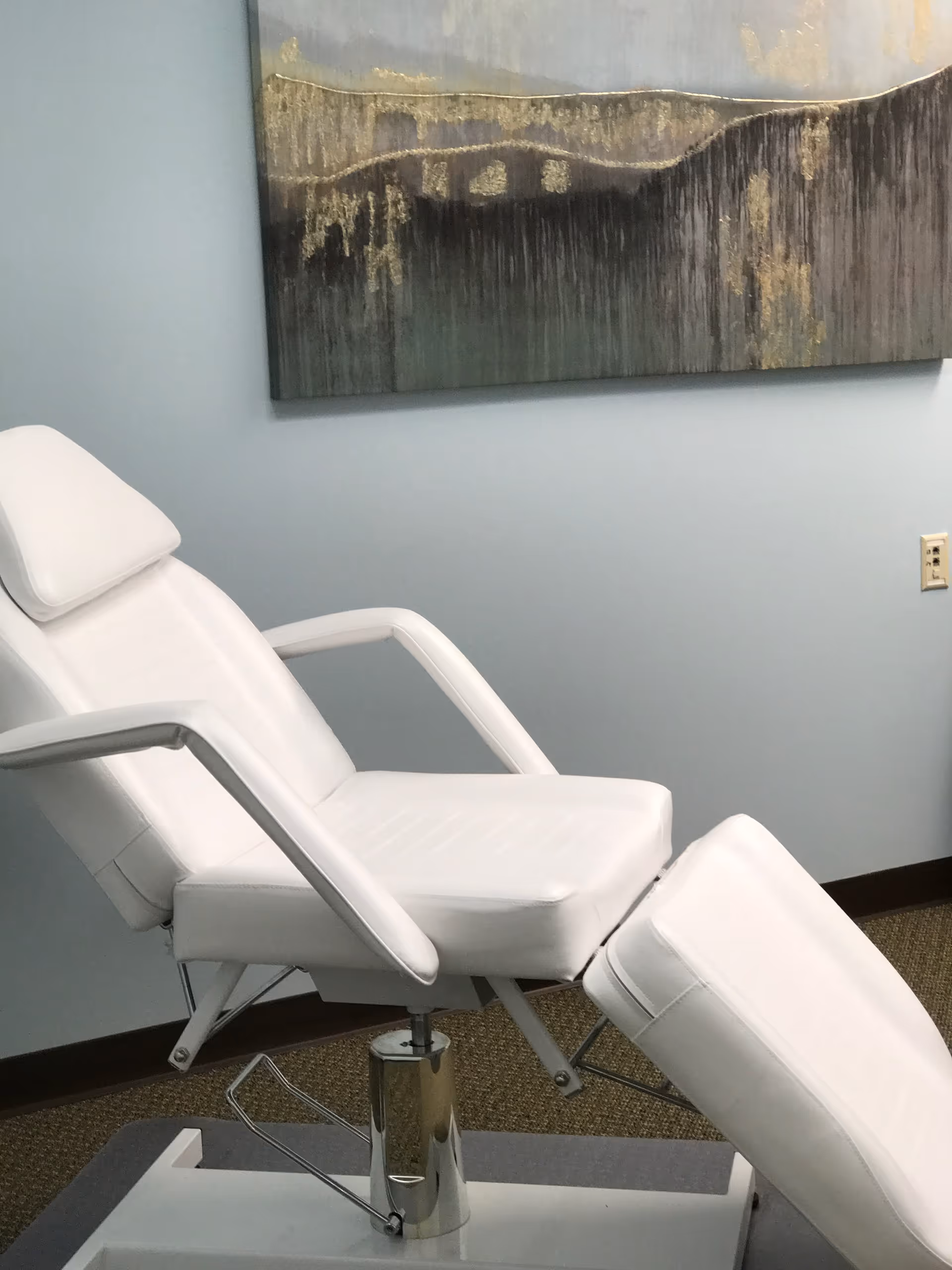 White reclining chair in a pale blue room with wall art.