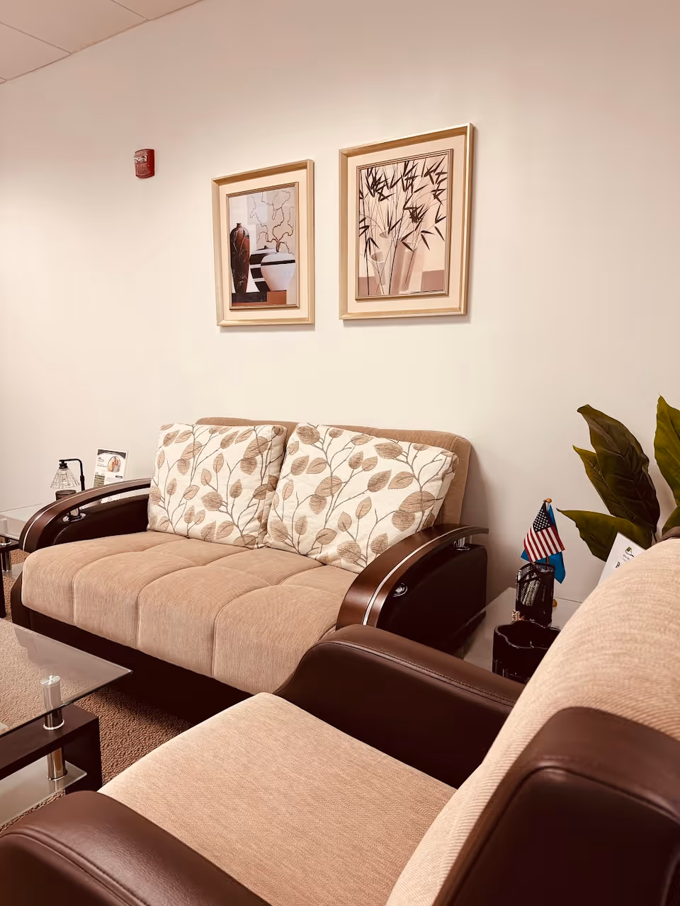 Cozy lounge area with beige couches, decorative pillows, framed art, and a small plant.