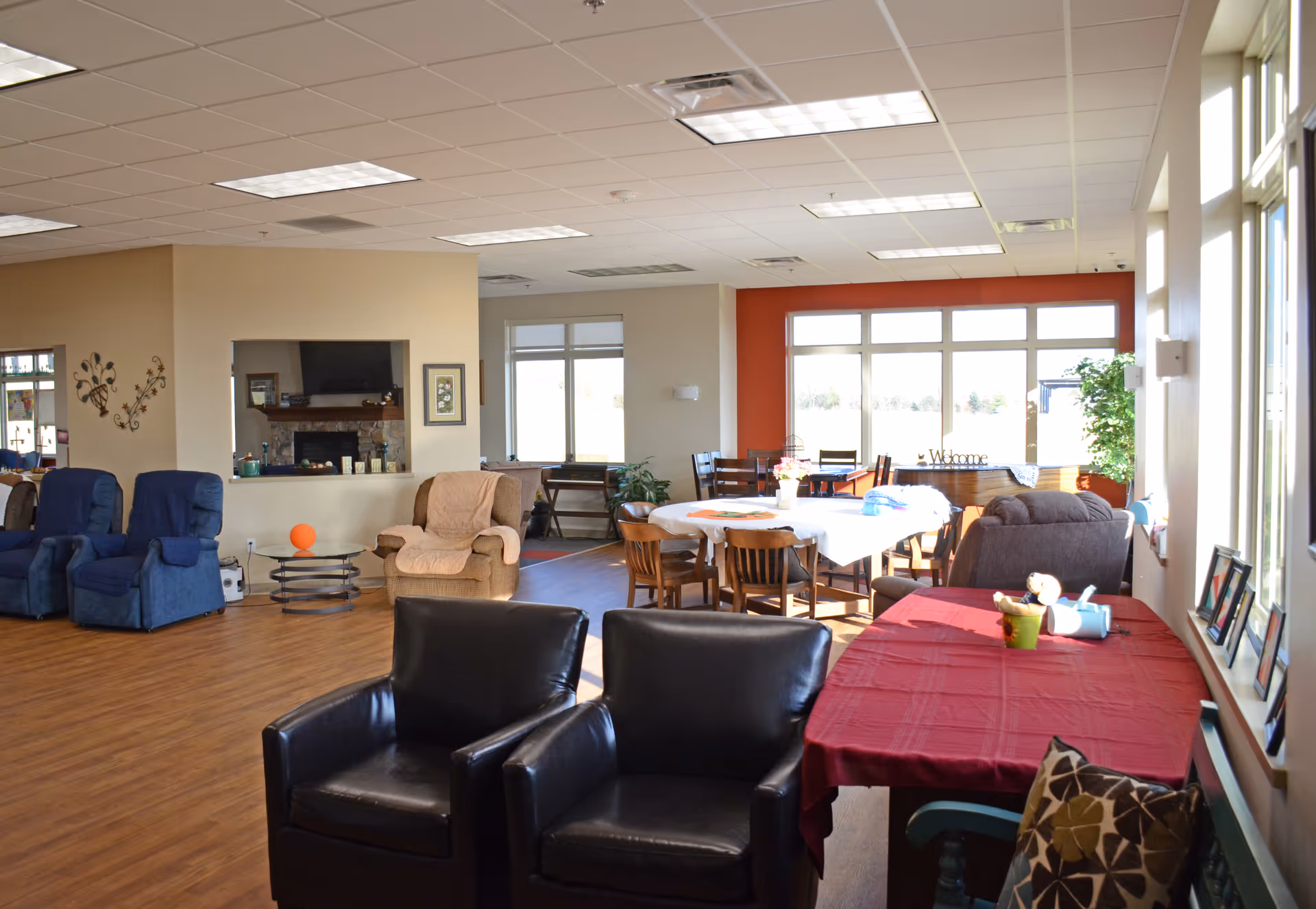 Spacious indoor common area with seating, tables, a fireplace, and large windows.