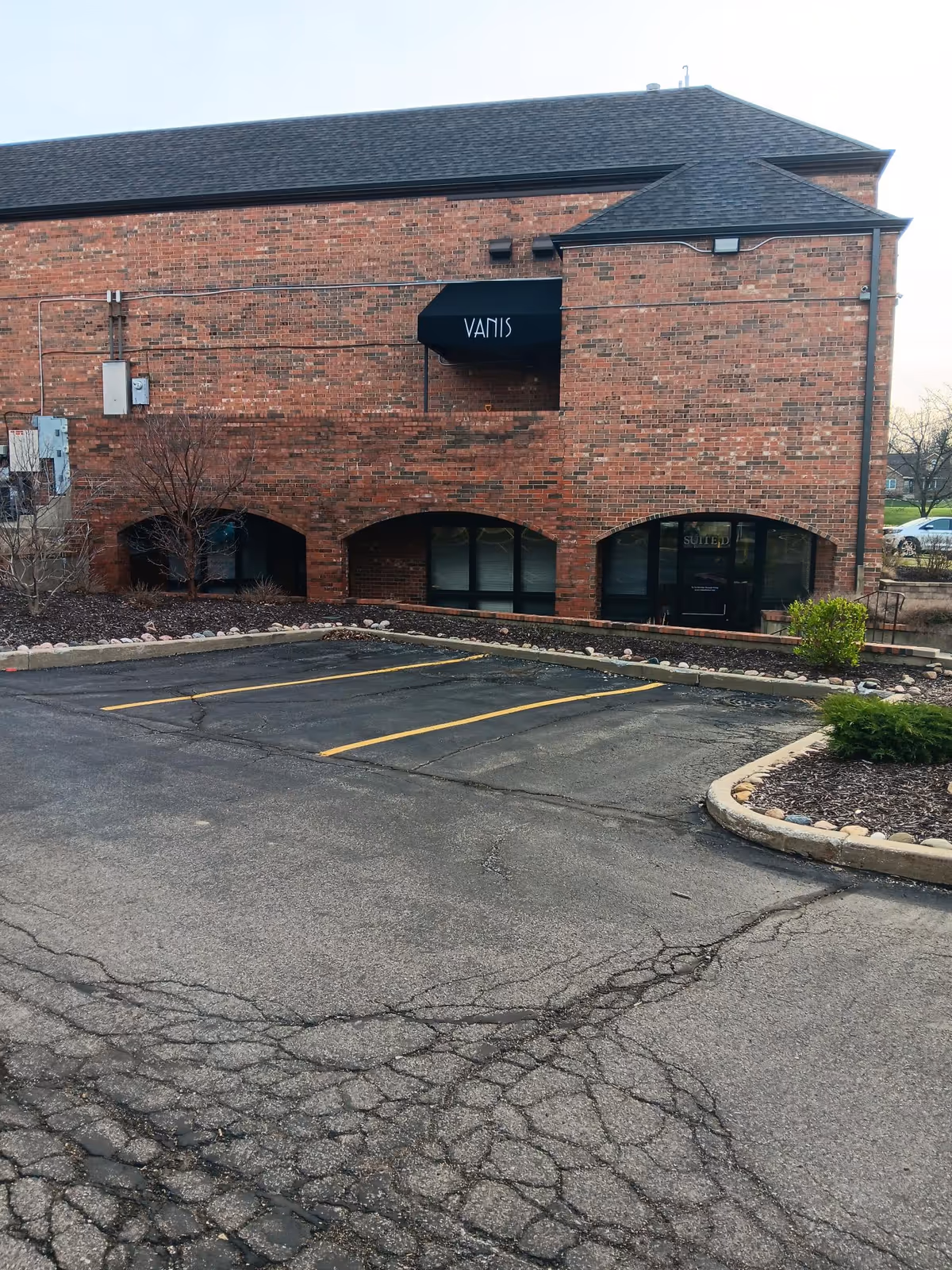 Brick senior-living building with a black awning and empty parking lot in front