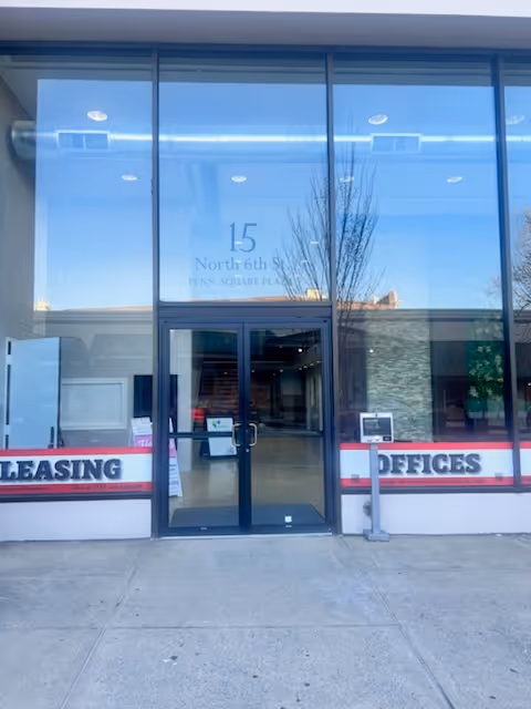 Glass storefront entrance with leasing offices signage and visible interior lobby.