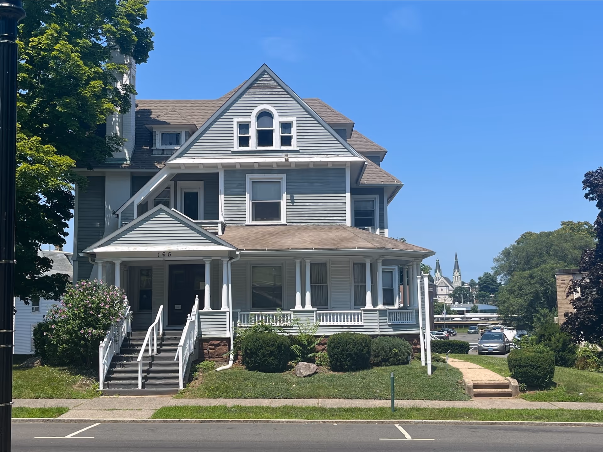 A large gray, multi-story house-style senior living building with a front porch.