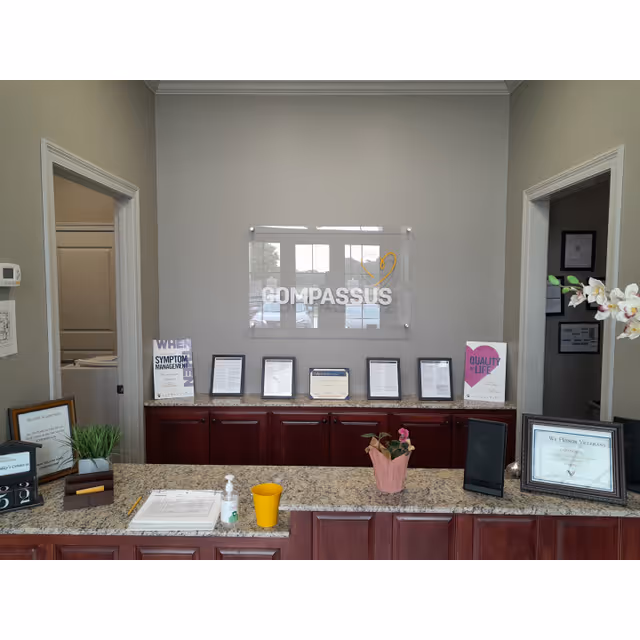 Indoor reception area with Compassus sign, granite counter, and framed documents.