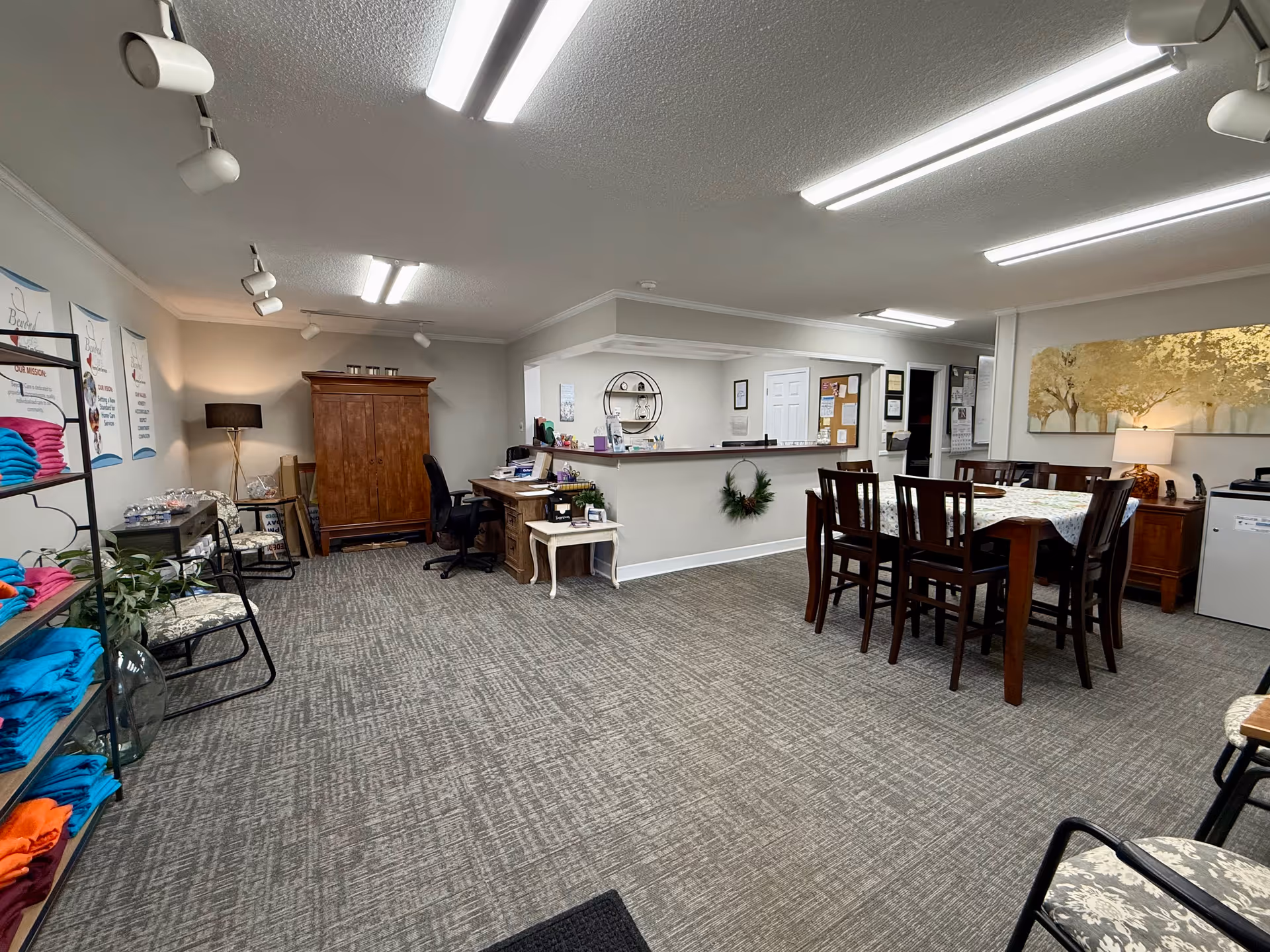 Interior common area with a reception desk, seating, dining table, and storage shelves.