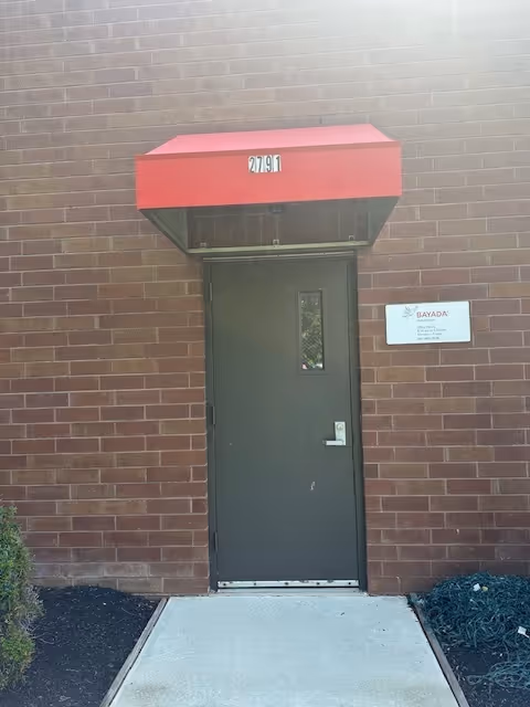 Brick exterior with a gray door, red awning, and BAYADA Habilitation sign.