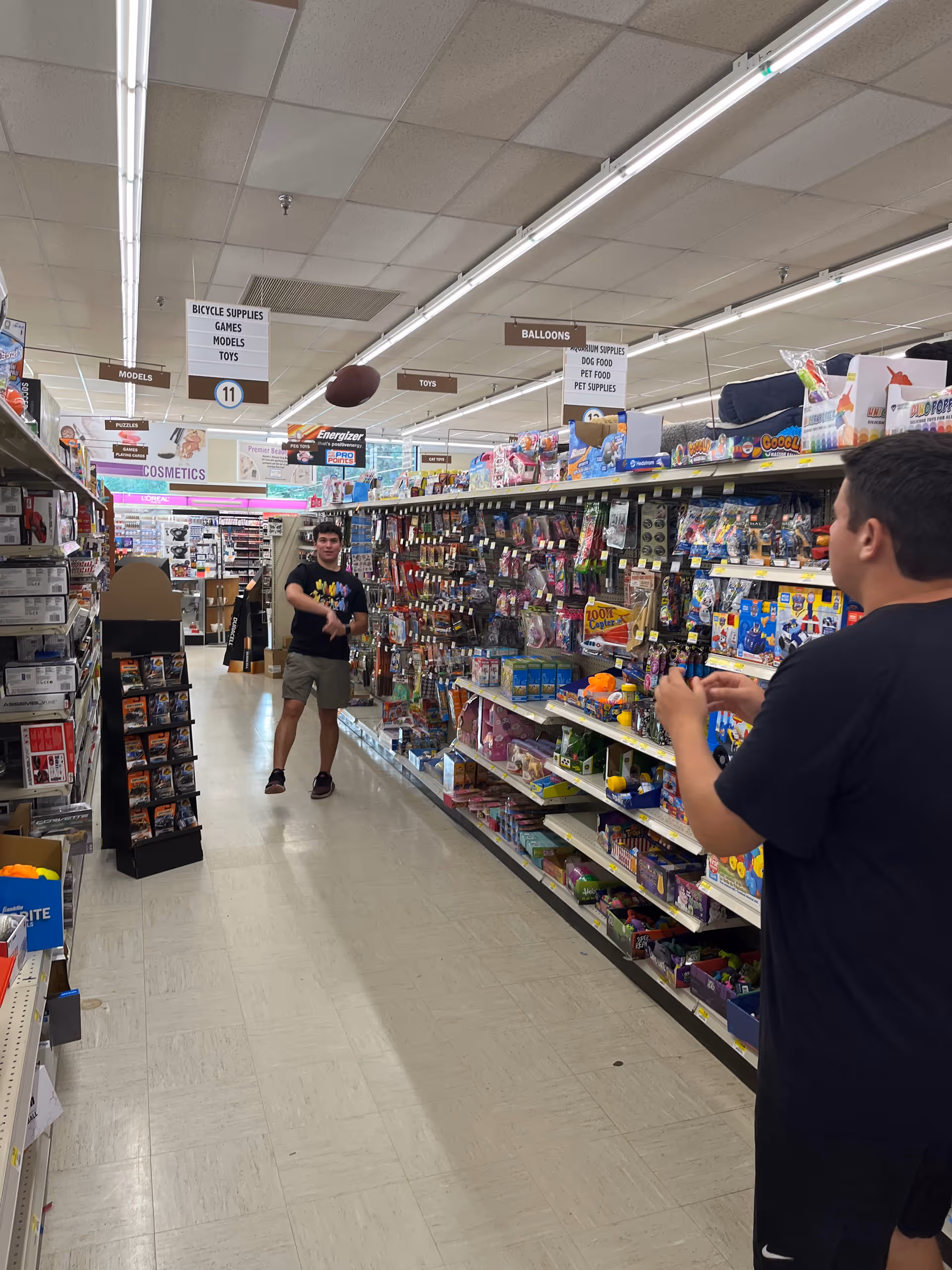 Two men in a Discount Drug Mart aisle with toys and supplies.