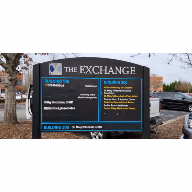 Outdoor parking lot sign reading 'The Exchange' displays building directory and Compassus logo.