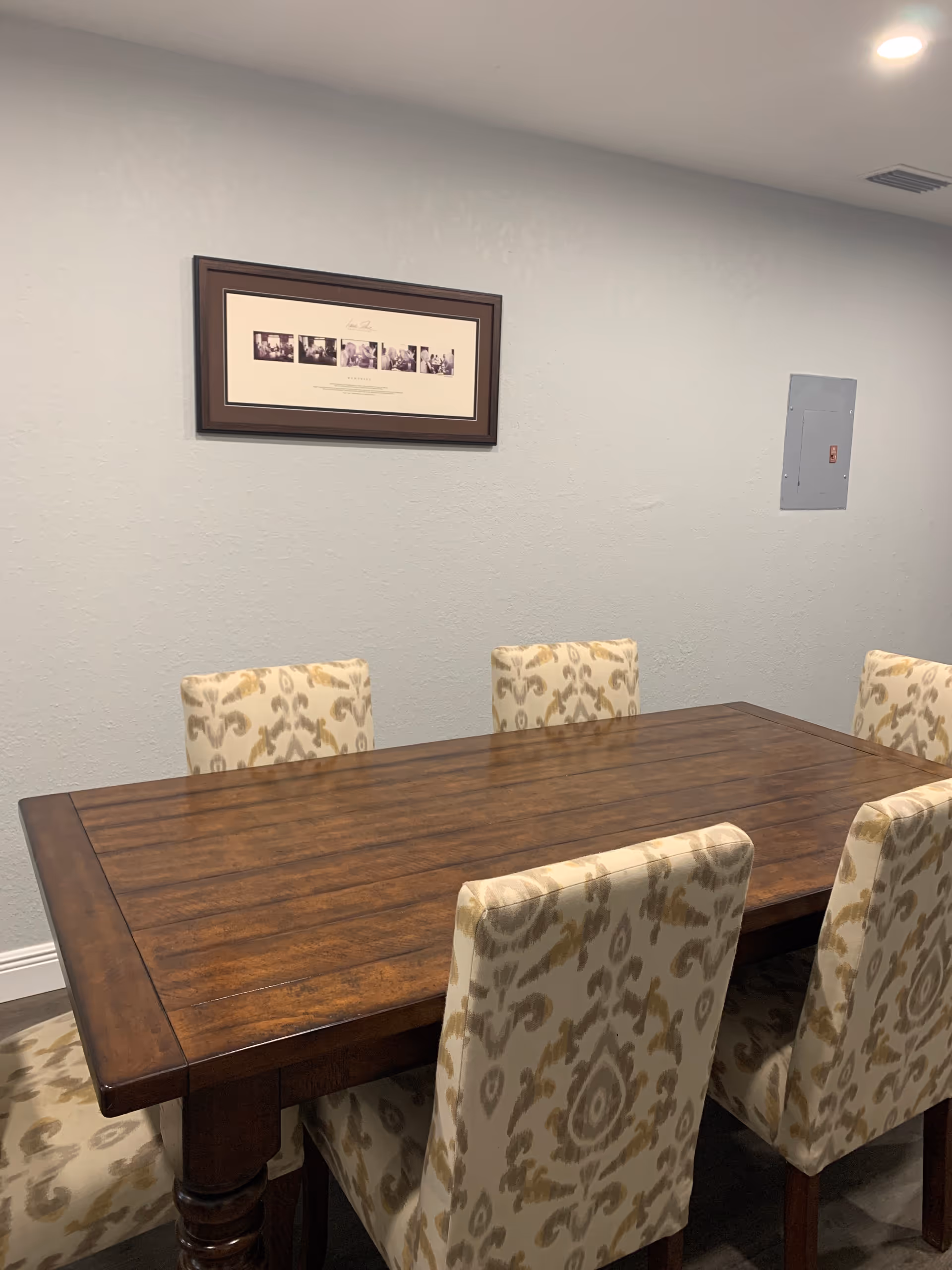 Wooden dining table with patterned chairs in a softly lit dining room.