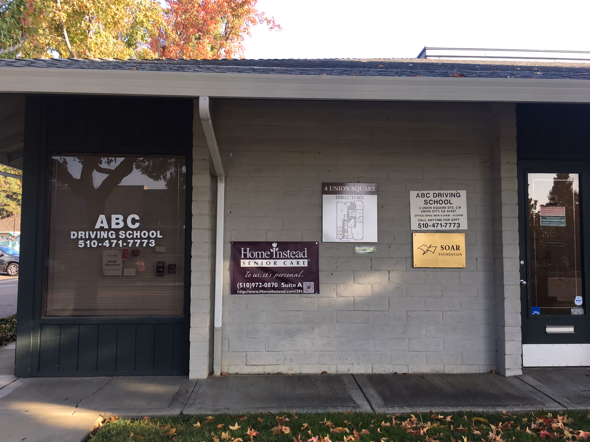 Gray building exterior with multiple signs for Home Instead and a driving school