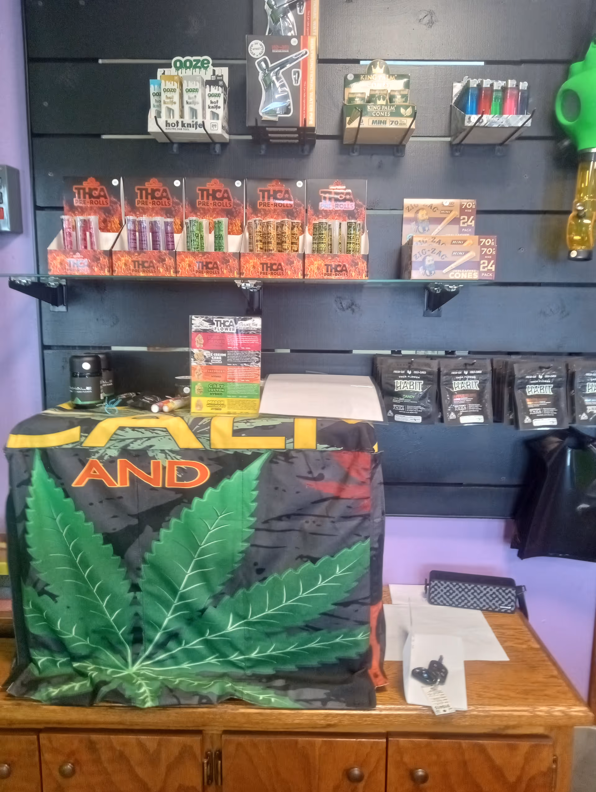 Indoor display area with cannabis products on shelves and a large leaf banner.