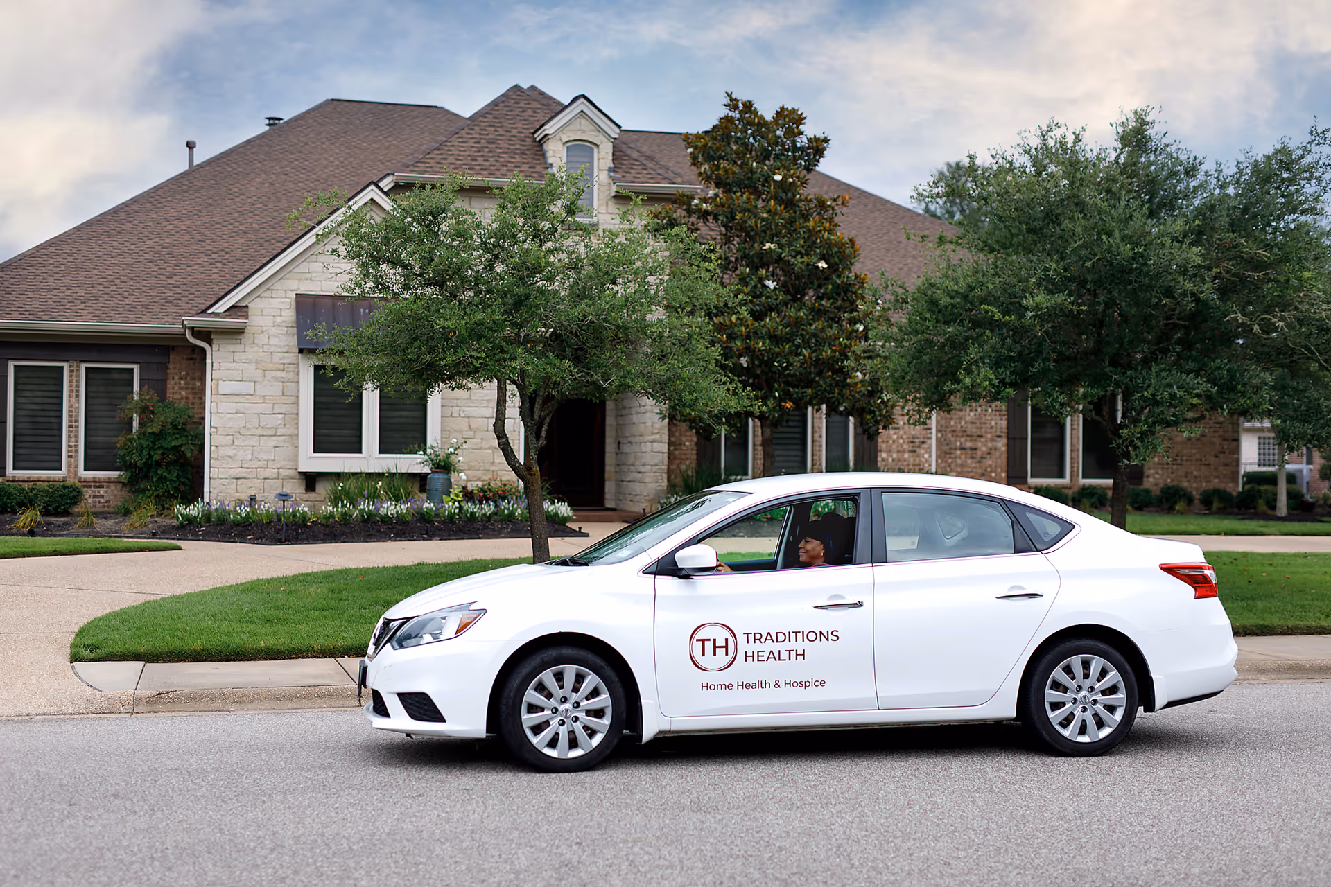 White car with Traditions Health logo parked in front of a stone-brick facility.