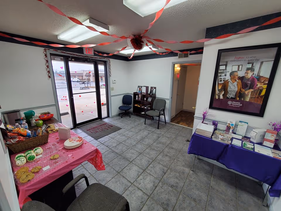 Home Instead lobby with refreshments table, brochures, and a poster near glass entrance.