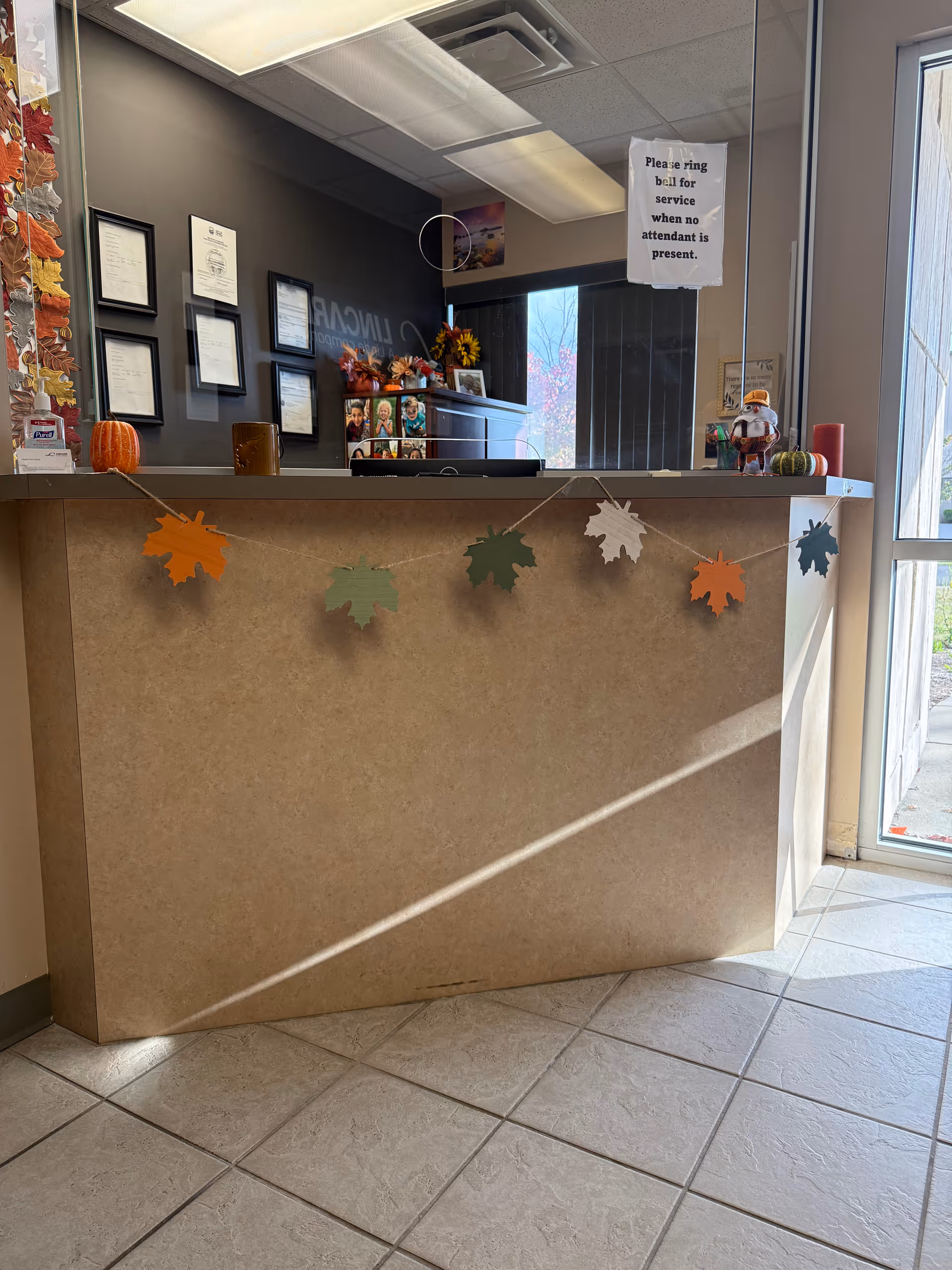 Interior reception desk with autumn garland, pumpkins, sunflowers, and framed certificates.