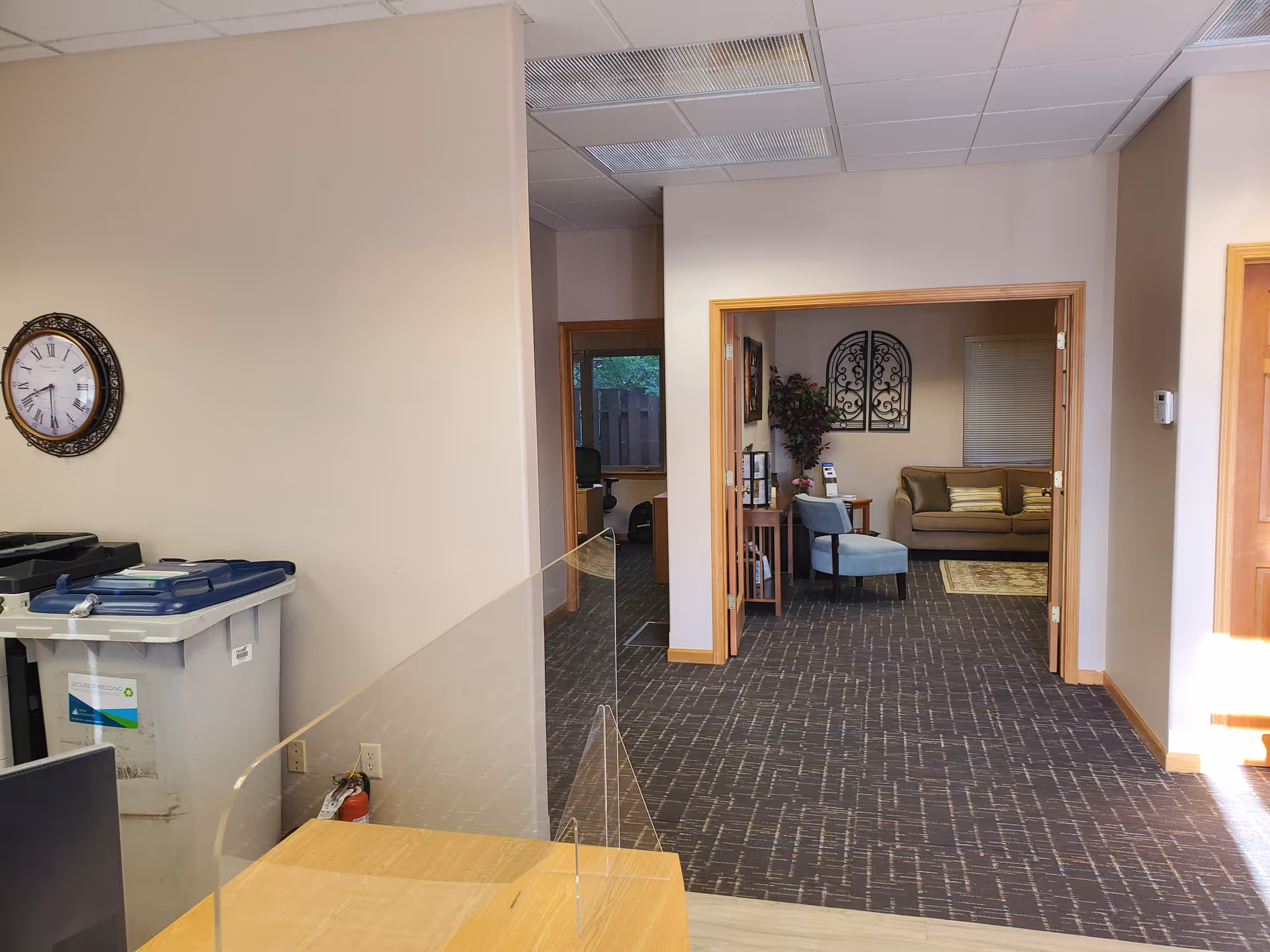Interior hallway with reception desk and lounge seating beyond a glass divider.