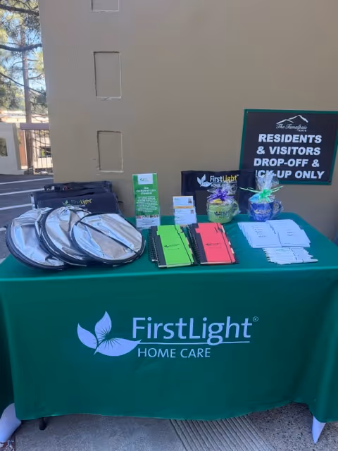 Outdoor table with FirstLight Home Care materials and sign against a beige wall.