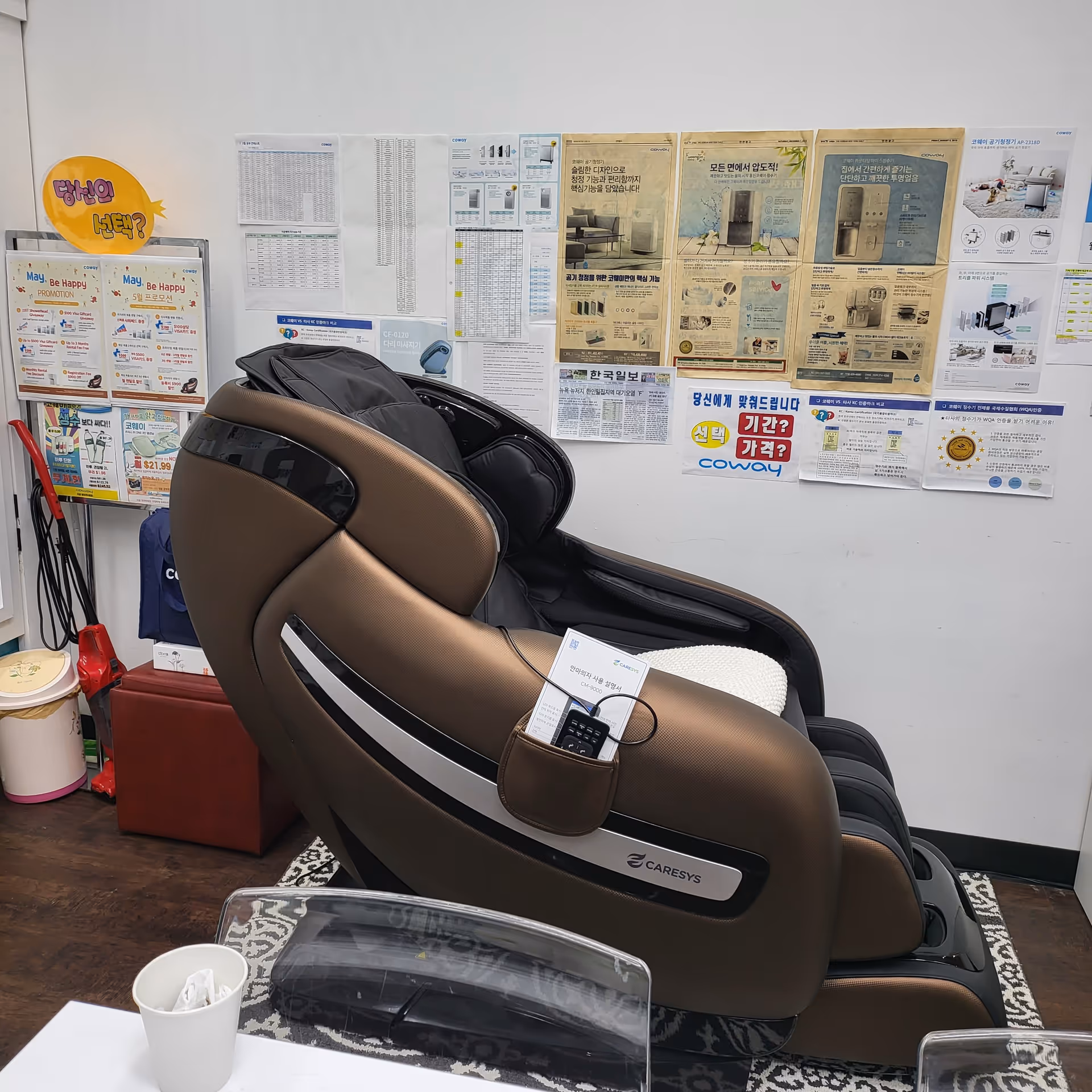 Brown massage chair in an interior space with wall posters and equipment.