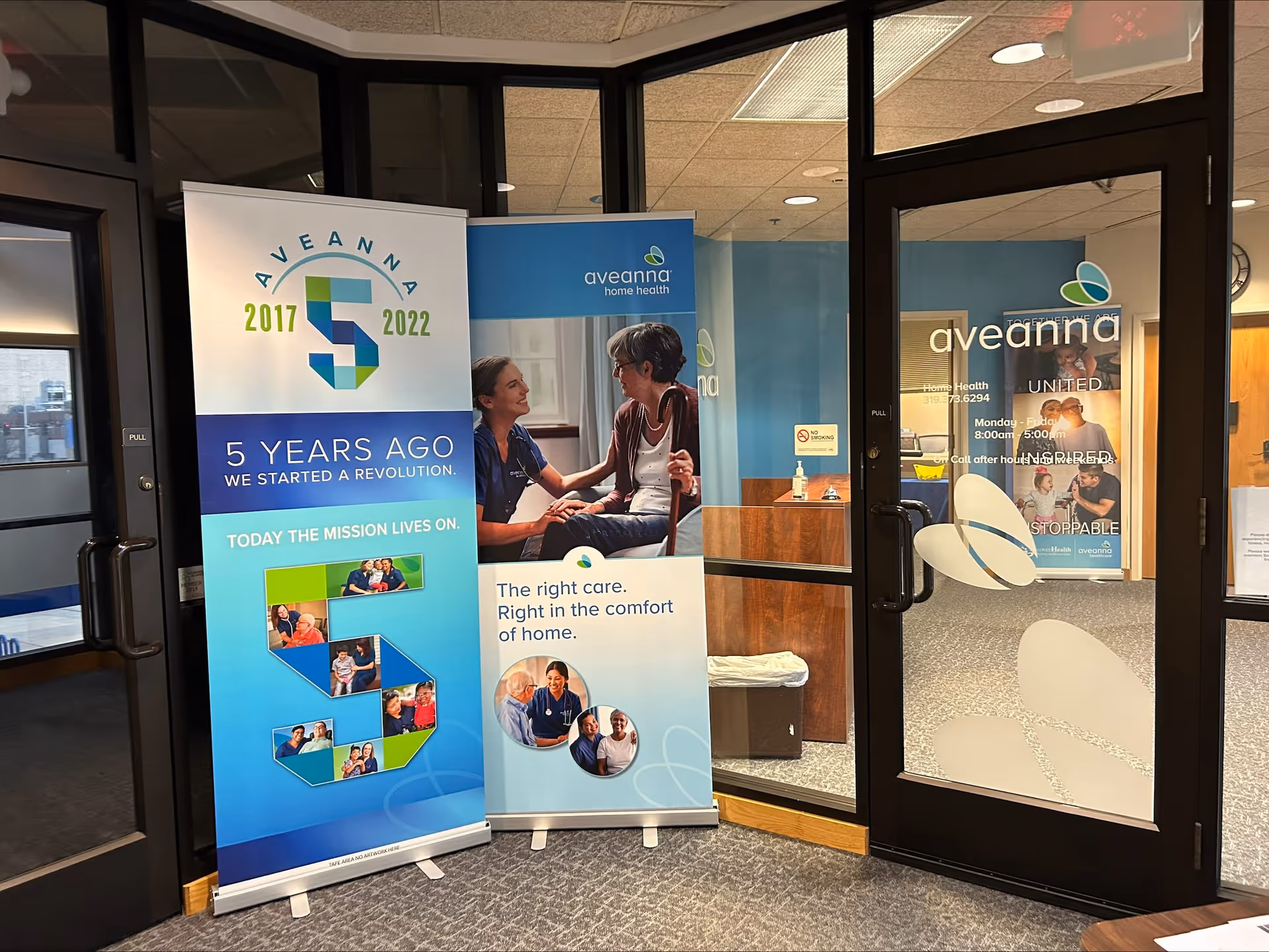 Interior lobby with three Aveanna banners displayed beside glass doors.