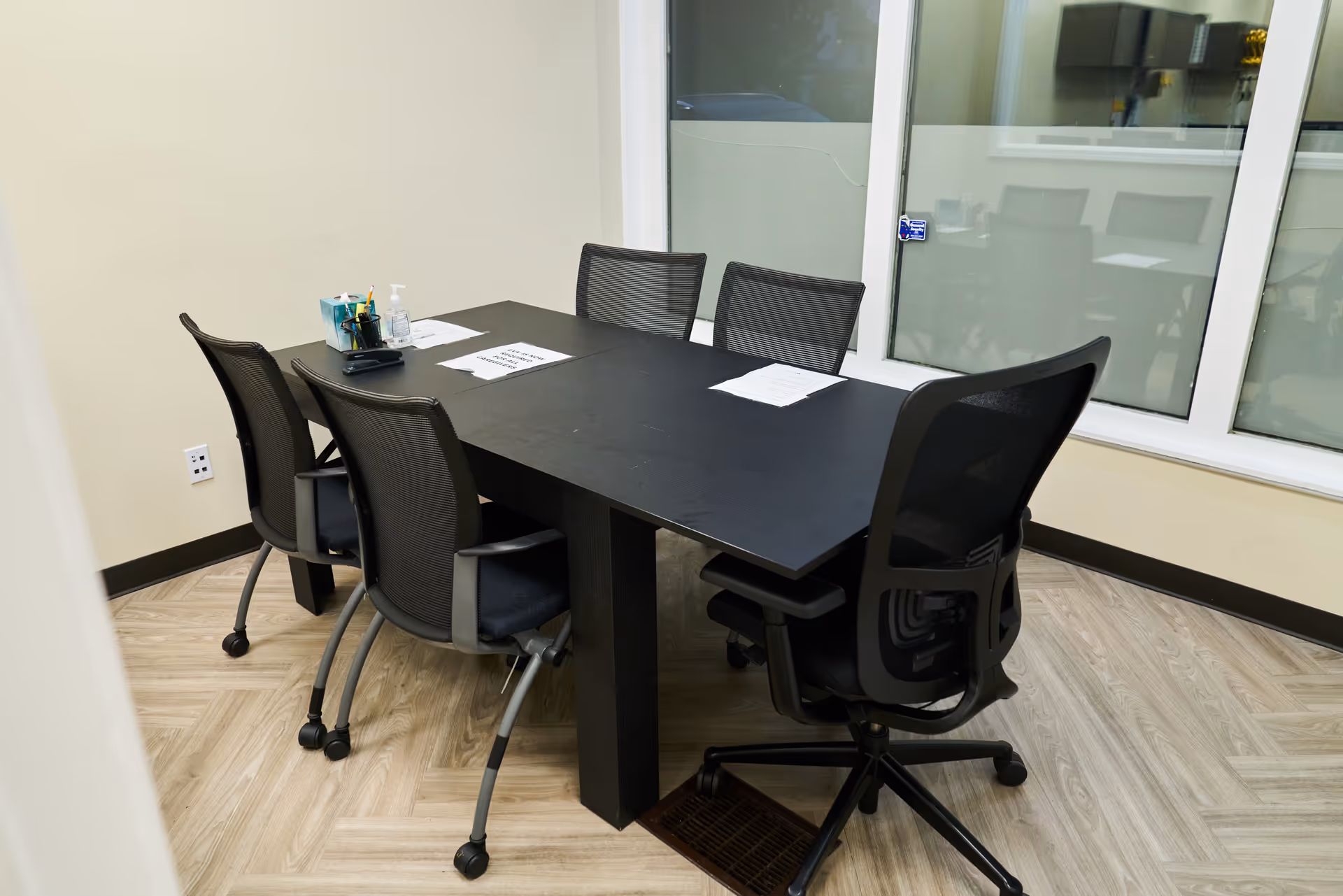 A rectangular conference table with chairs in a bright, empty meeting room.