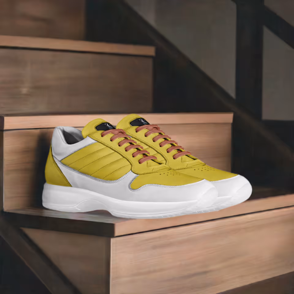 Yellow and white sneakers resting on wooden steps inside a dim interior.