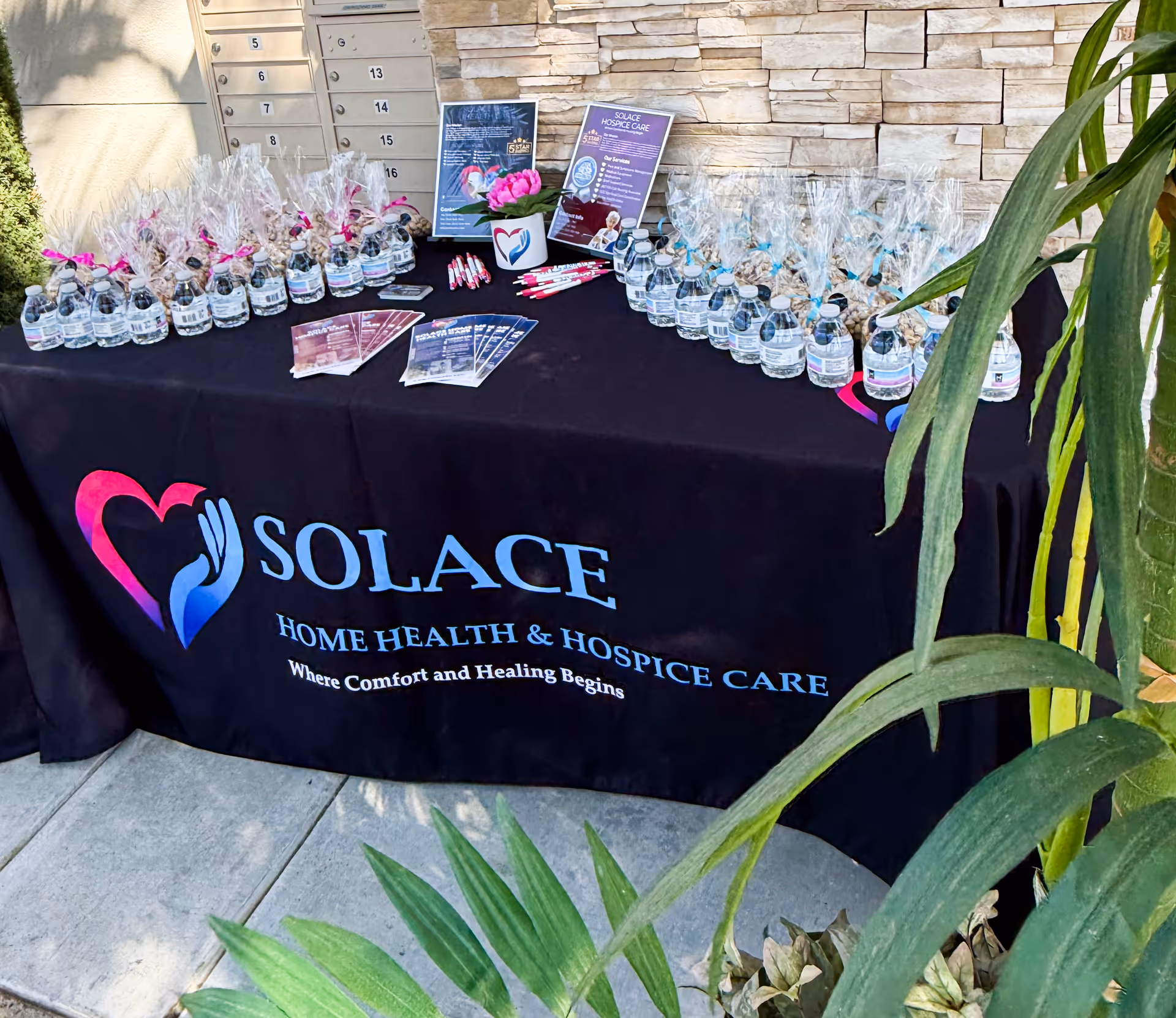 Outdoor promotional table with Solace Home Health & Hospice Care branding and bottled water.