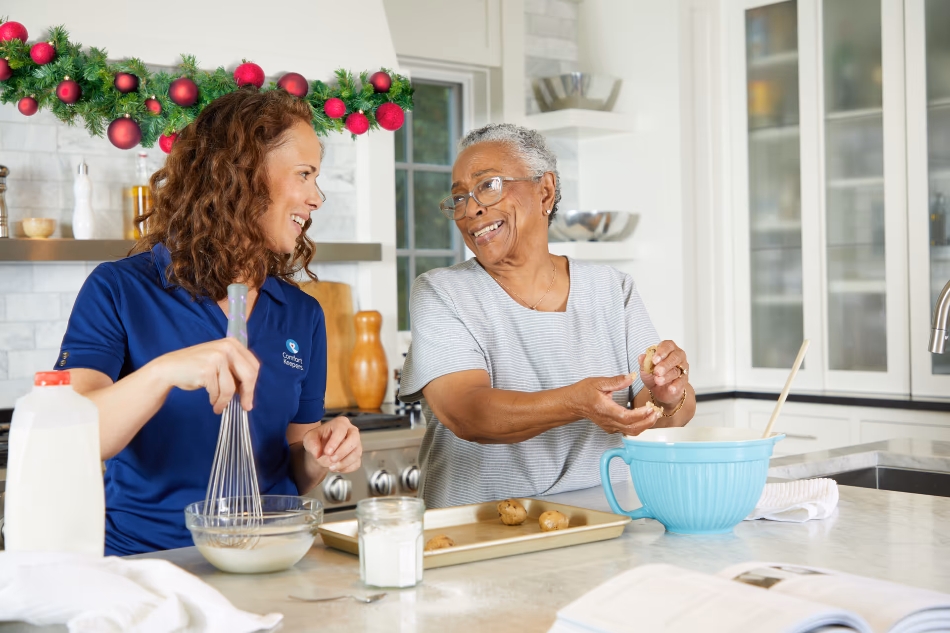 Caregiver and elderly resident bake together in a bright, modern kitchen.