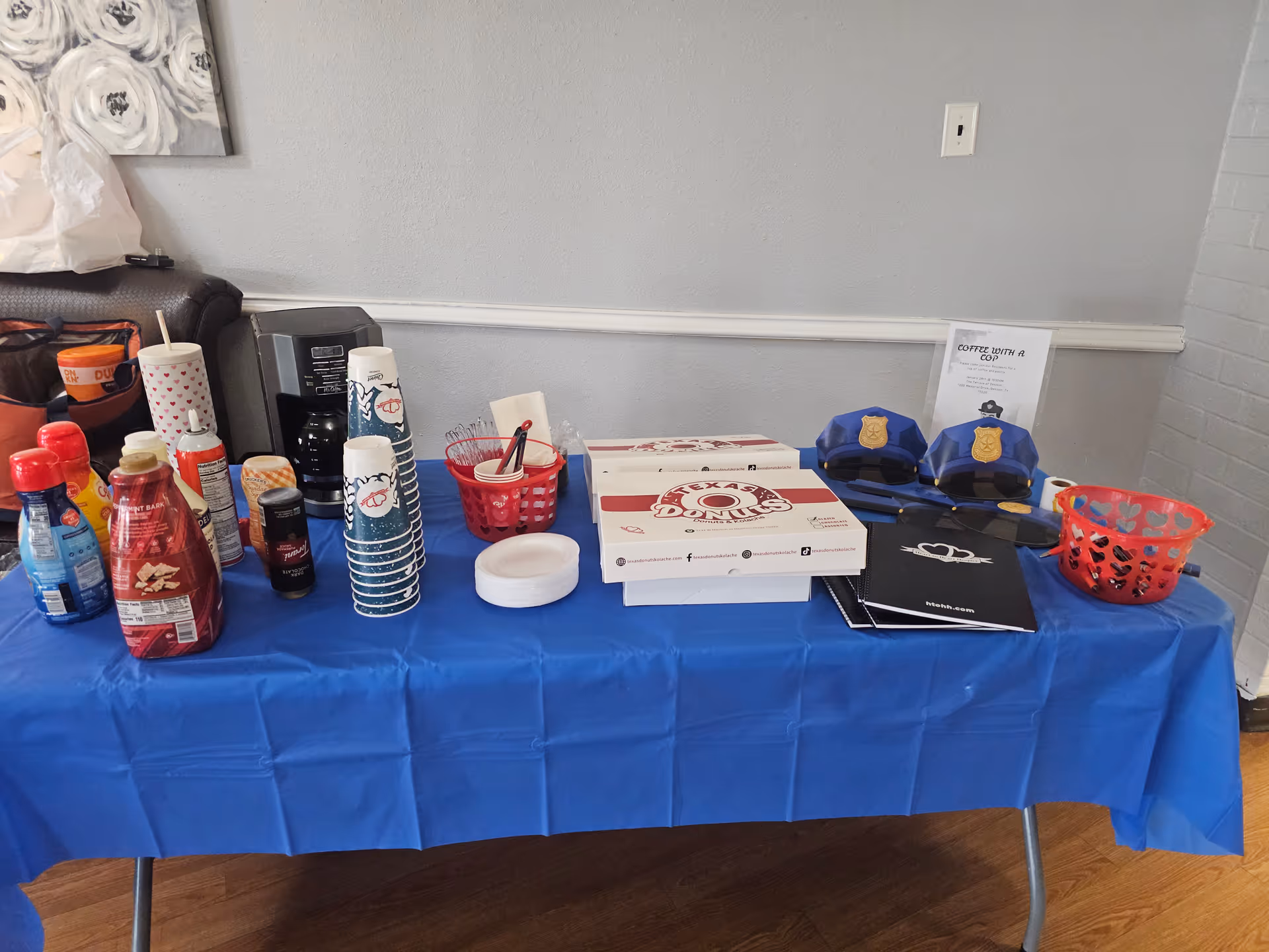 Refreshment table covered with blue cloth, snacks, cups, napkins, and event flyers.