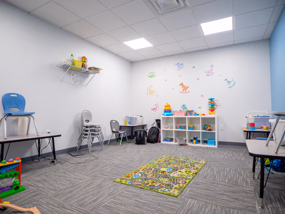Bright interior playroom with toy shelves, mats, and colorful wall decals.