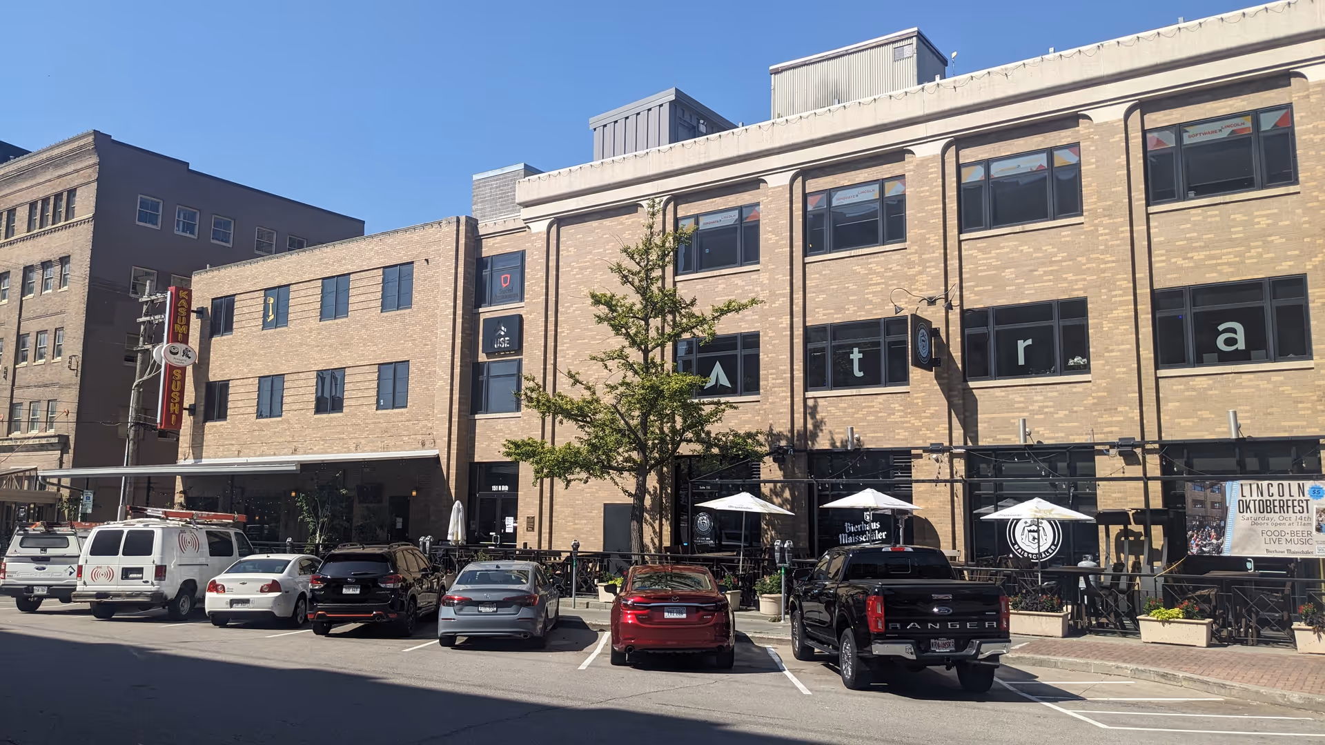 Exterior view of Independent Horizons with outdoor seating along a brick building and parked cars.