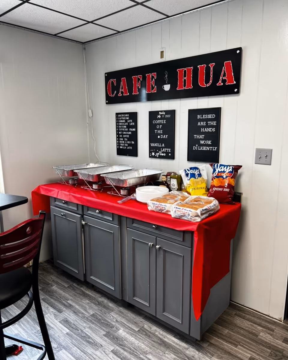 Cafe-style buffet area with chafing dishes, chips, and bread on a red-clothed counter.