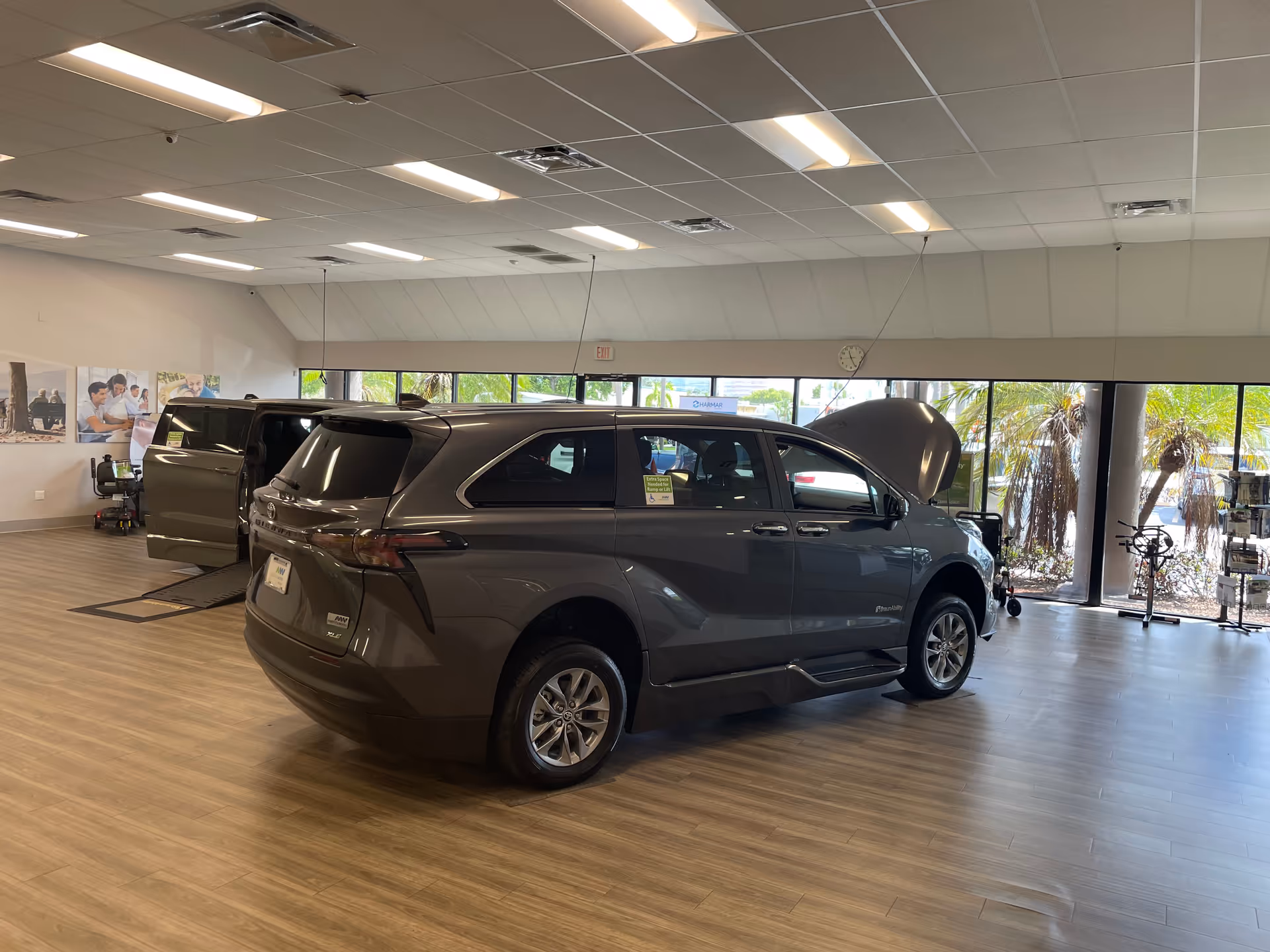 Inside a MobilityWorks showroom, a gray minivan is on display with its hood open.