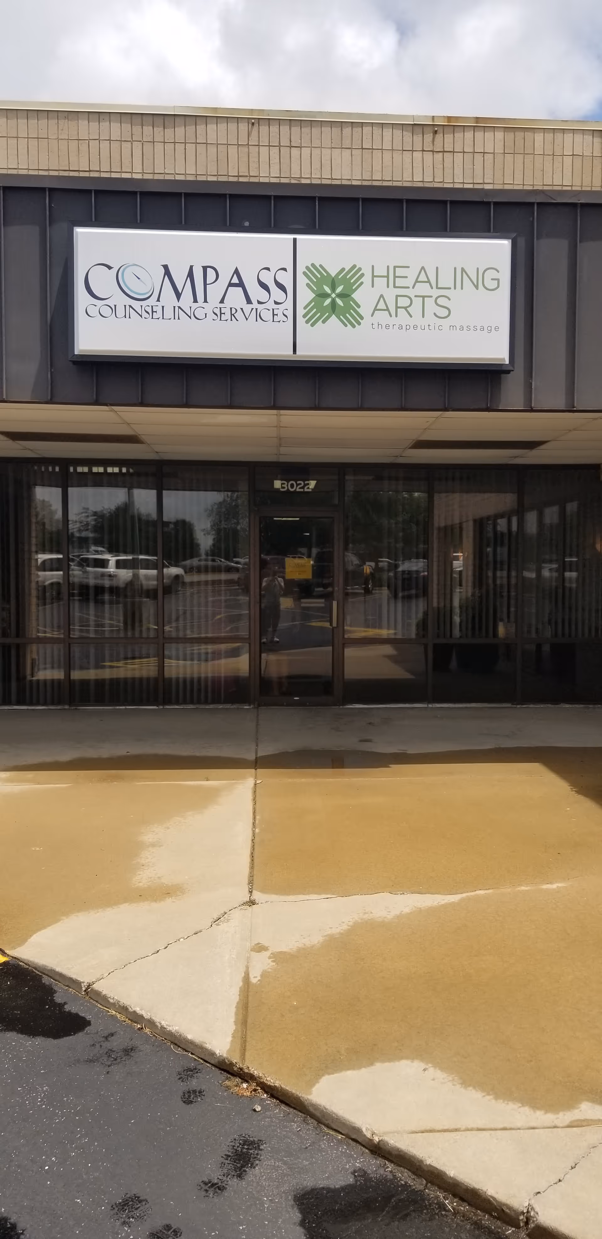 Exterior of a commercial building with glass doors and two storefront signs.