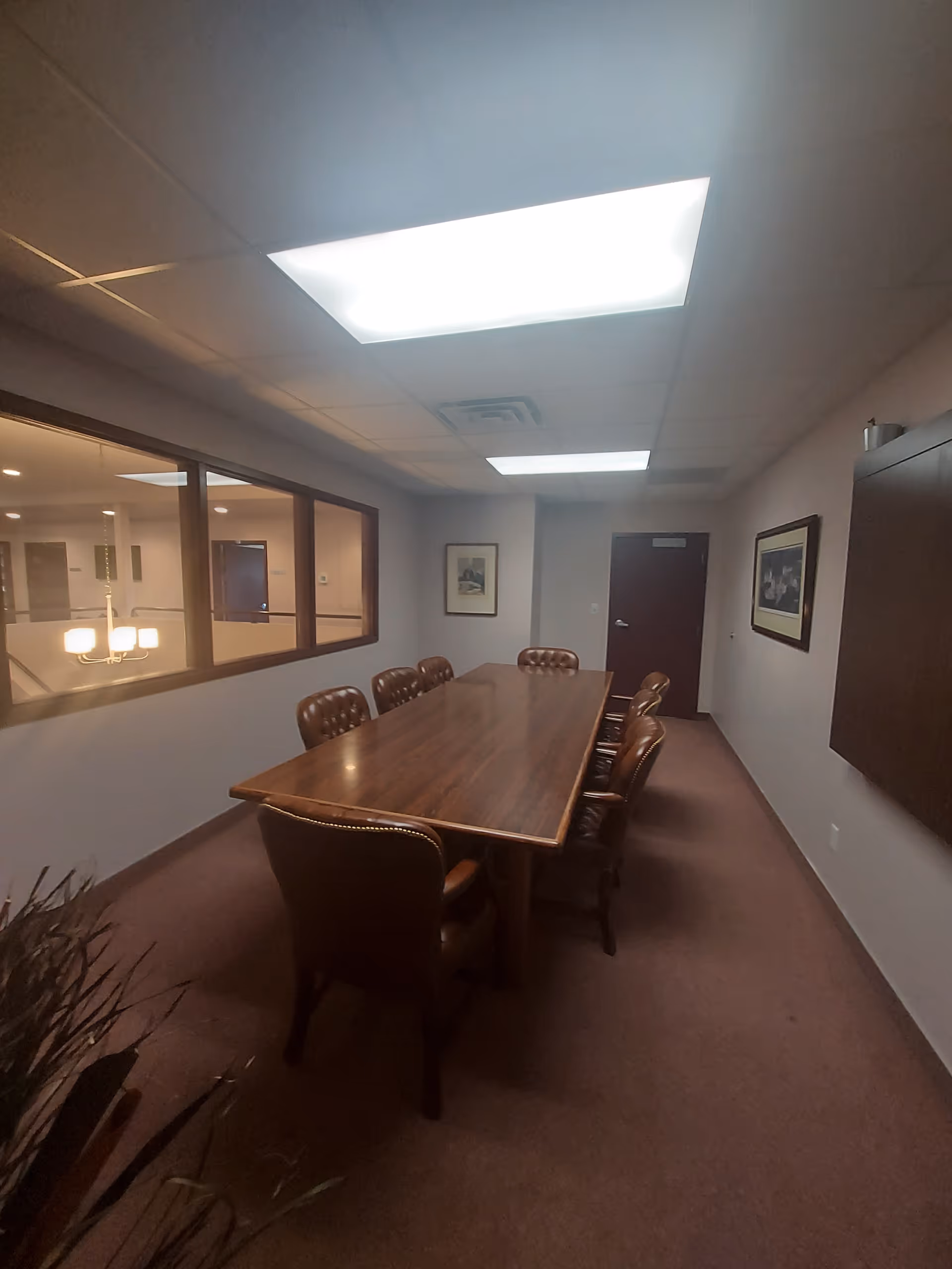 Long wooden table with brown leather chairs in a quiet senior home conference room.