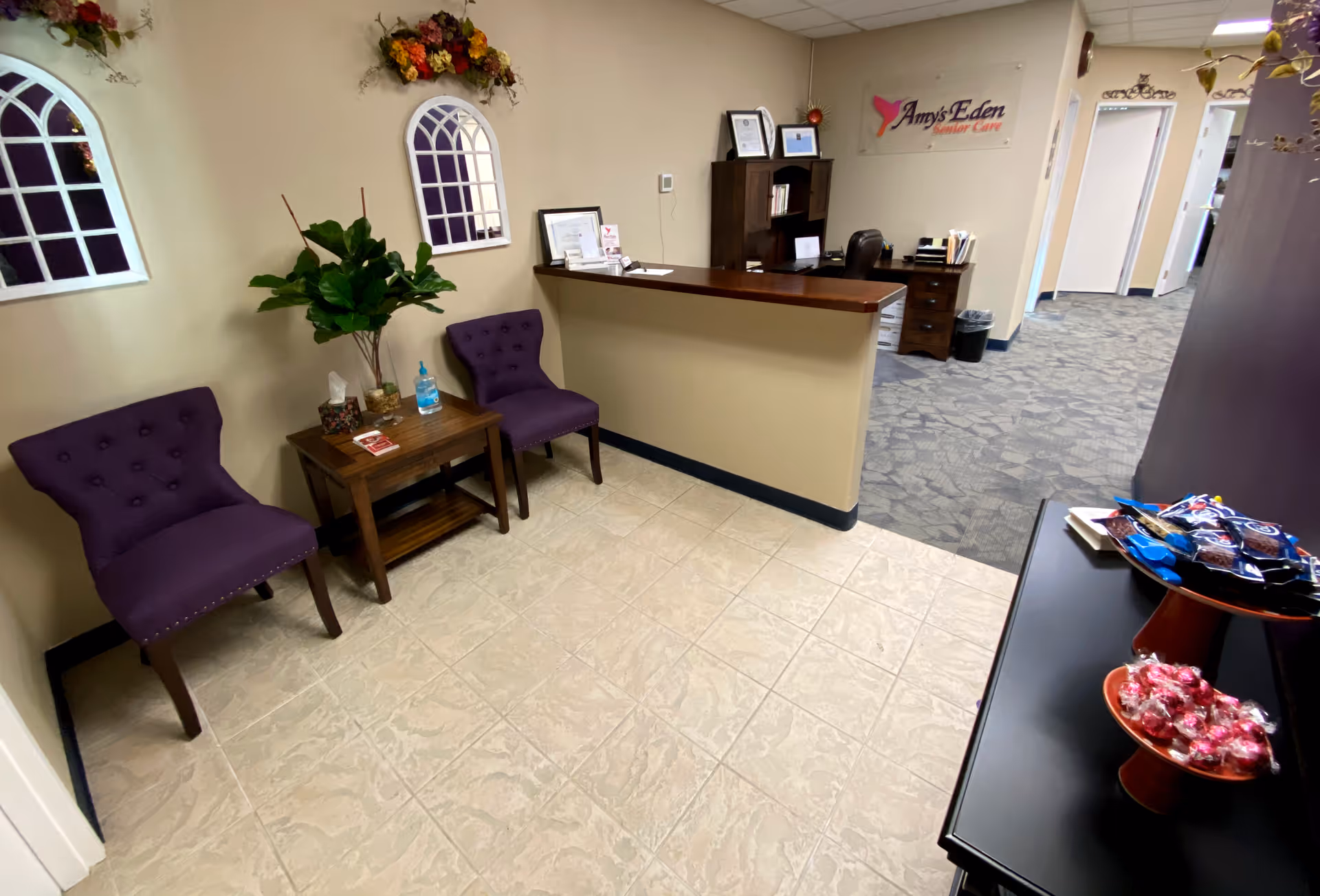 Lobby seating area at Amy's Eden Senior Care with purple chairs and front desk.